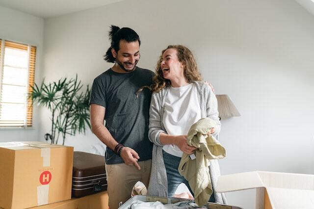 Two people laughing together while packing up a suitcase